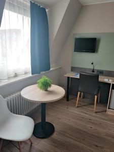 een kamer met een tafel, een stoel en een tv bij Hotel Corsten in Heinsberg