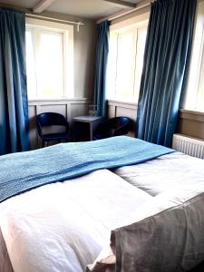 a bedroom with a bed with blue curtains and two chairs at Hraunsnef Country Hotel in Bifrost