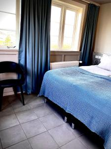 a bedroom with a bed and a chair and a window at Hraunsnef Country Hotel in Bifrost