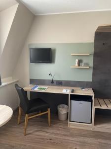Zimmer mit einem Schreibtisch mit Stuhl und einem TV in der Unterkunft Hotel Corsten in Heinsberg