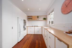a kitchen with white cabinets and a clock on the wall at The Blue House in Havelock North