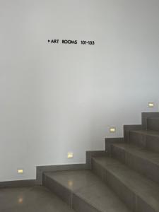 a white wall with stairs with a sign that reads eat rooms toonox at Kanes Boutique Hotel in Sarandë