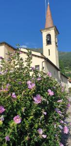 a building with a clock tower with purple flowers at Residence Laguna Beach in Pianello Del Lario