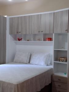 a bedroom with a white bed with wooden cabinets at Casa Mariano in Brotas