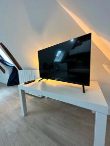 einen großen Flachbild-TV auf einem weißen Tisch in der Unterkunft T2 atypique et chaleureux in Baugé