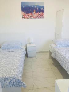a white room with two beds and a night stand at Villa Sole Tisno in Tisno