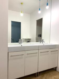 een witte badkamer met 2 wastafels en een spiegel bij Grand Appartement - Tour Eiffel in Parijs