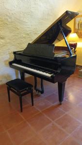 un piano negro sentado en una habitación con un taburete en Le Vieux Moulin, en Jouques