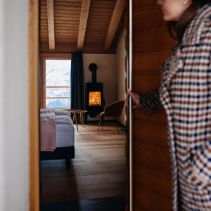 a woman opening a door to a room with a fireplace at nif: alpine taste in Levico Terme