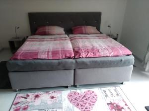 Una cama con sábanas rosas y almohadas rosas. en Ferienwohnung Sonnenblick, en Oberharmersbach