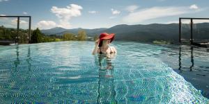 a woman in a red hat in a swimming pool at Sonnenhof Resort Himmelreich Bayerischer Wald in Lam