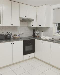 uma cozinha com armários brancos e uma máquina de lavar louça preta em STS 21, Nicosia-Lakatamia one-bedroom Apartment em Kato Lakatamia