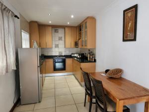 a kitchen with a wooden table and a refrigerator at Six Valk Avenue Guest House in Johannesburg