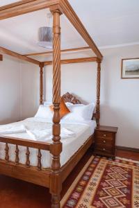 Wild Amboseli Ndovu Cottage. في أمبوسيلي: سرير بأربعة أعمدة خشبي في غرفة بها سجادة