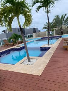 a swimming pool with two palm trees next to a building at Apartamento em Maceió a beira mar in Maceió