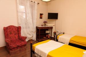 a bedroom with two beds and a chair and a television at Olga's Cozy home in Monemvasia