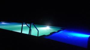 einen Pool in der Nacht mit blauen und grünen Lichtern in der Unterkunft SANDSTAR PALACE in Merzouga