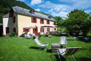 un groupe de chaises assises dans l'herbe devant une maison dans l'établissement Gite Auberge Les Cascades, à La Mongie