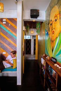 a hallway with a painting on the wall and two people in a room at Happiness Hostel El Nido in El Nido