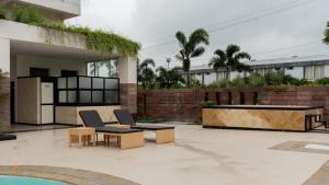 un patio con 2 sillas, una mesa y una piscina en Monk's Nirvanaa Hotel & Resort en Indore