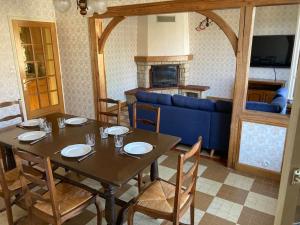 a dining room with a table and a blue couch at Longère du Perche in Montigny-le-Chartif