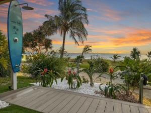 a boardwalk leading to a beach with palm trees and a surfboard at Paradise Palms Tangalooma in Tangalooma