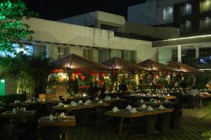 Monk's Nirvanaa Hotel & Resort في إندوري: مطعم بطاولات خشبية امام مبنى في الليل