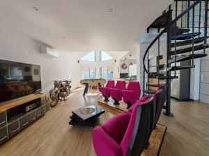 a living room with pink chairs and a staircase at L'Effet Mer, maison d'exception in Berck-sur-Mer