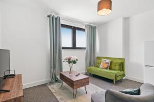 a living room with a green couch and a table at Heathrow Haven: Stylish Apartments in the Heart of Slough in Slough