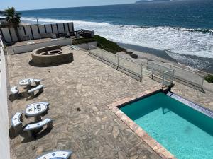 a swimming pool next to a beach with the ocean at Hermoso Departamento frente al Mar in Tijuana