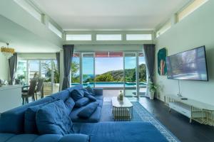 a living room with a blue couch and a tv at Cozy 5BR Villa Stunning SeaViews in Kamala Beach
