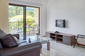 Creole Breeze Self Catering Apartments في ماهي: غرفة معيشة مع أريكة وطاولة زجاجية