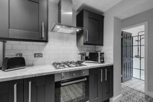 a black and white kitchen with a sink and a stove at 4 bedroom stylish home central location in Liverpool