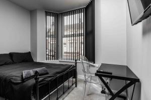 1 dormitorio con cama, escritorio y ventana en 4 bedroom stylish home central location en Liverpool