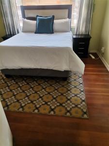 um quarto com uma cama com uma almofada azul e um tapete em Delightful Home em Pretoria