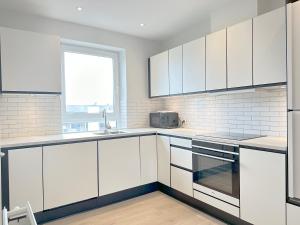una cucina bianca con mobili bianchi e una finestra di Beautiful Apartment In The Heart Of Aalborg ad Aalborg