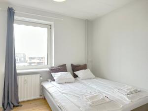 un letto bianco in una stanza con una finestra di Beautiful Apartment In The Heart Of Aalborg ad Aalborg