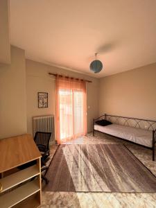 1 dormitorio con cama, escritorio y ventana en Άνετο διαμέρισμα - Κέντρο Ξάνθης, en Xanthi