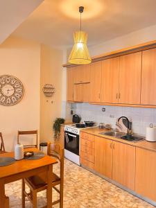 una cocina con armarios de madera, mesa y fregadero en Άνετο διαμέρισμα - Κέντρο Ξάνθης, en Xanthi