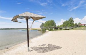 um guarda-sol de palha numa praia com a água em Beautiful Home In Nowe Warpno With Wifi em Nowe Warpno