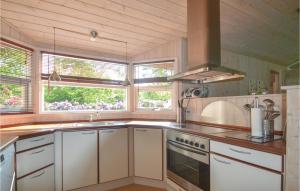 uma cozinha com armários brancos, um lavatório e janelas em Awesome Home In Glesborg With Kitchen em Fjellerup Strand
