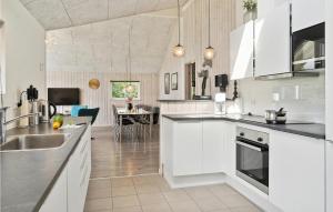 a kitchen with white cabinets and a dining room at Amazing Home In Stege With Sauna in Stege