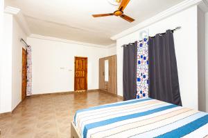 a bedroom with a bed and a ceiling fan at Grand appartement lomé centre ville mer clim 6pers in Lomé