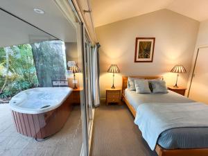 1 dormitorio con bañera y 1 cama en Lake Russell Lakeside Retreat, en Emerald Beach