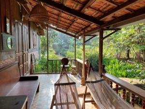 two hammocks on a porch with a view of the forest at Charming Countryside Homestay in Ben Tre