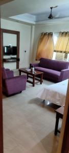 a living room with purple couches and a table at Hotel Shiva Krishna(Unit of Nandan Udyam Pvt Ltd) in Patna