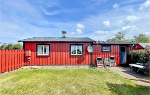 a red house with two chairs and a fence at 2 Bedroom Cozy Home In Degerhamn in Degerhamn