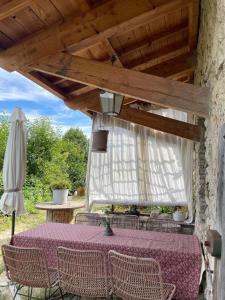 a table and chairs under a wooden roof at Les Vignals gîtes et événements Cévennes in Arphy