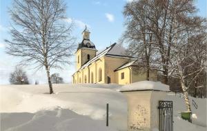 una iglesia con una torre de reloj en la nieve en Lovely Home In Ramvik With Kitchen, en Ramvik