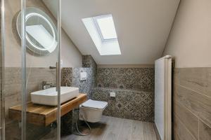 a bathroom with a sink and a toilet and a skylight at Pansion "Fawlty Towers" Sarajevo in Sarajevo